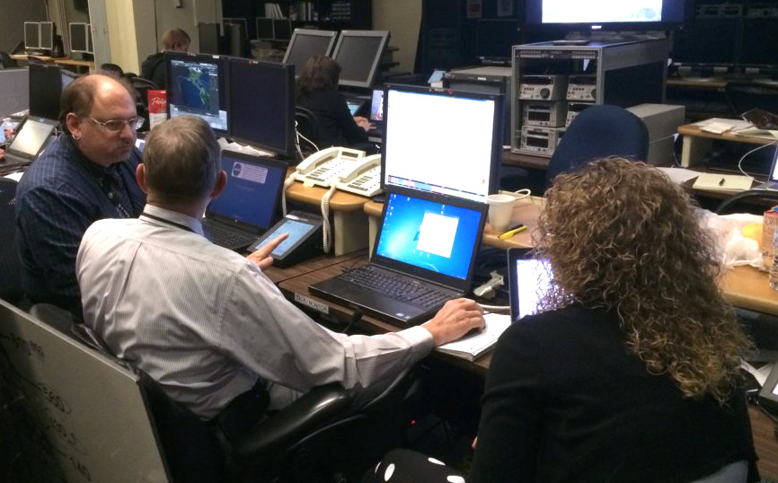 3 team members deep in discussion in mission control.