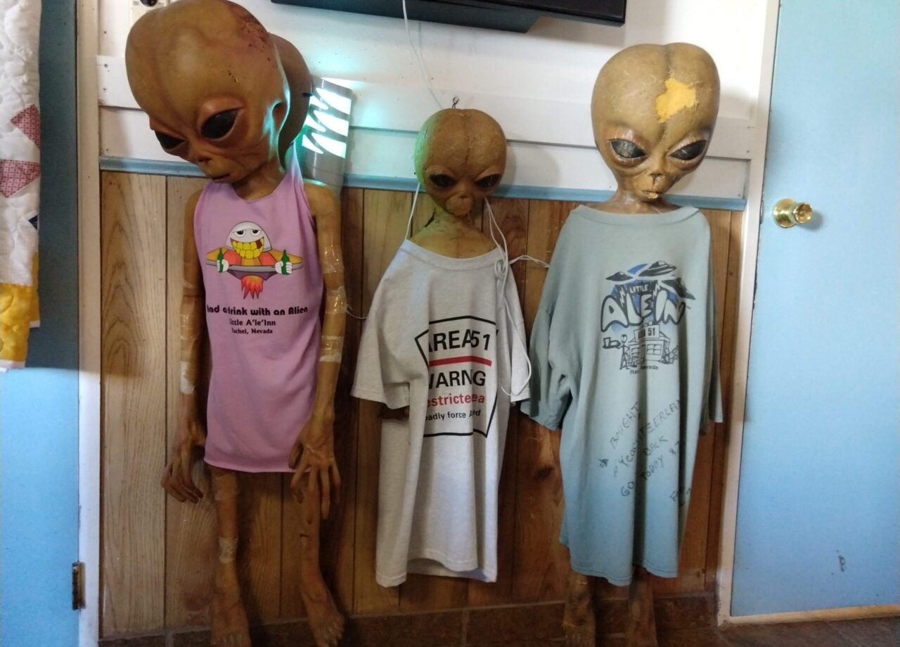 Three alien mannequins wear alien themed t-shirts.