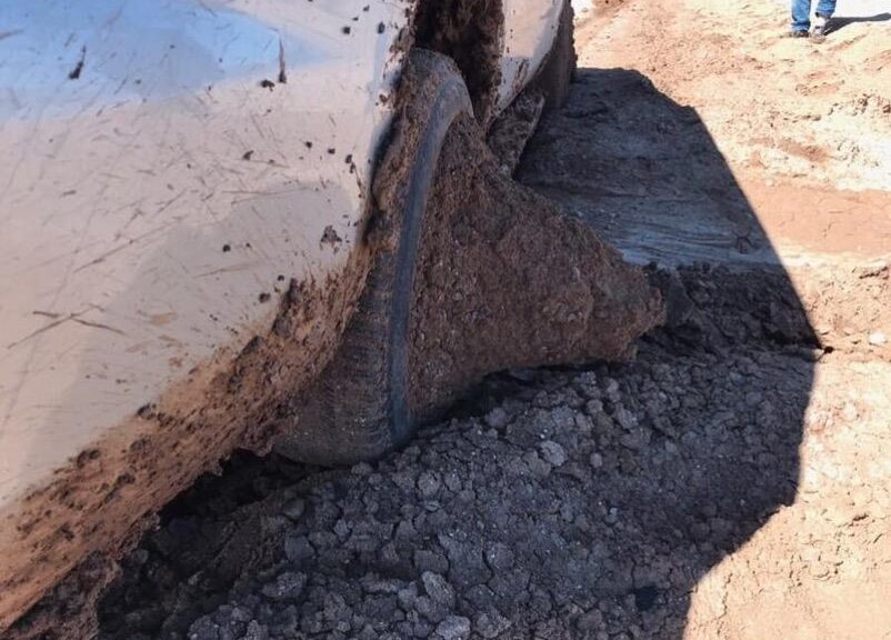 A car with a tire so caked in mud that the dirt forms a cone-like shape in the center of the tire.