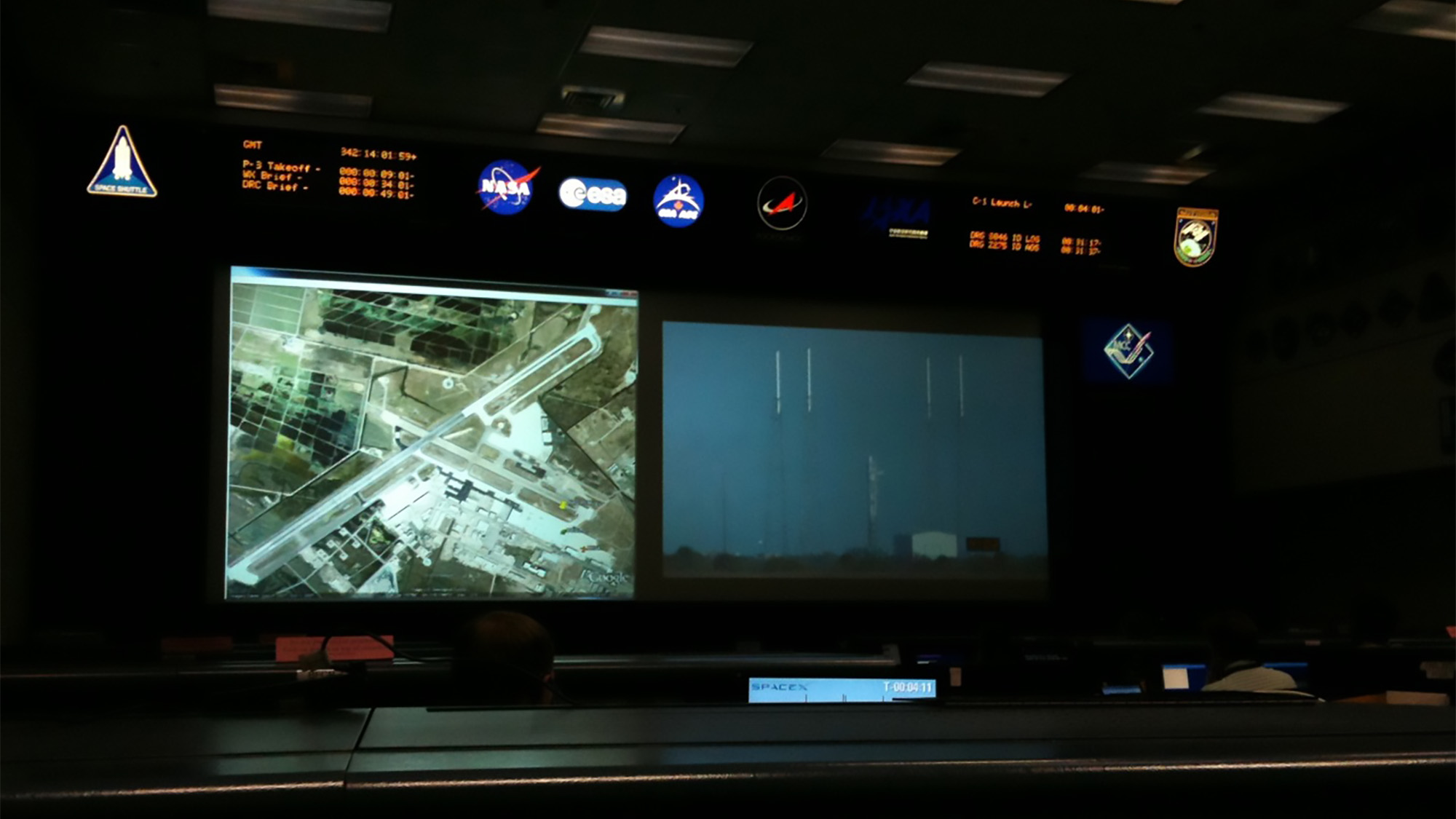 mission control display, showing an overhead view of launch site and several illuminated logos, including NASA and Spacex