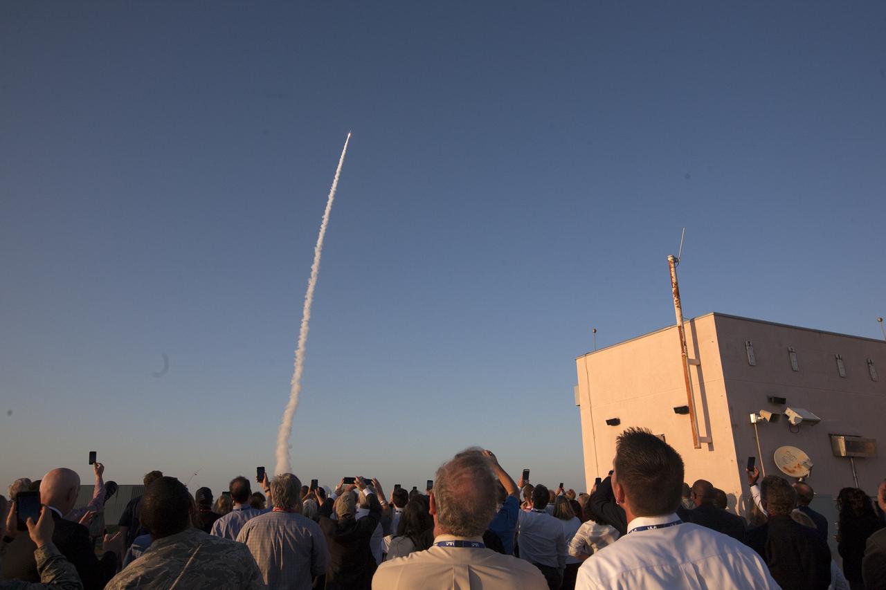 A group of people watch the path of a rocket through the sky.